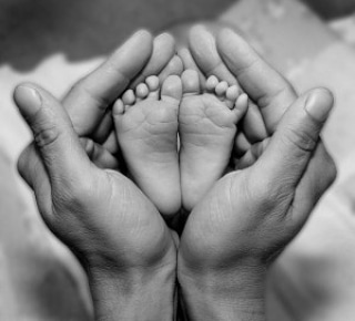 pieds d'un tres jeune bebe dans les main d'un adulte